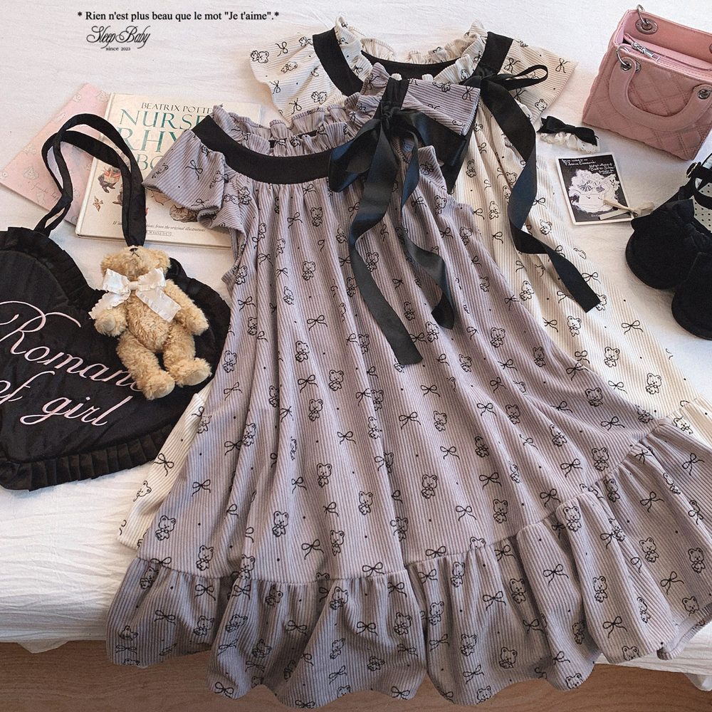 Patterned dress with black ribbons on a bed with books and bags