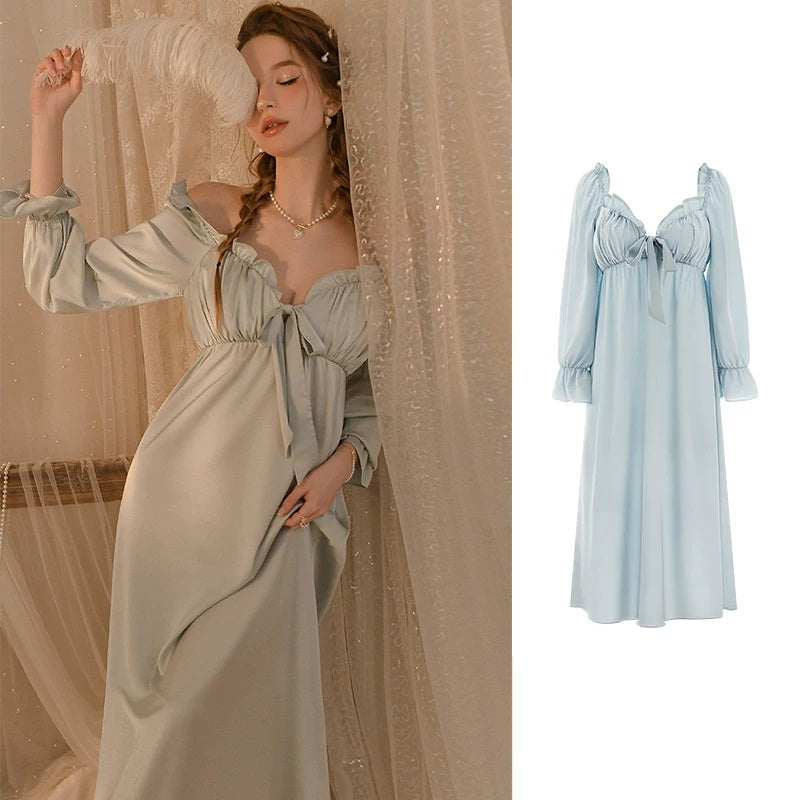 A woman wearing a light sage green off-the-shoulder maxi dress with long puff sleeves and a front bow detail, posed in front of sheer curtains. A smaller inset on the right shows the same dress in a pale blue color against a white background.