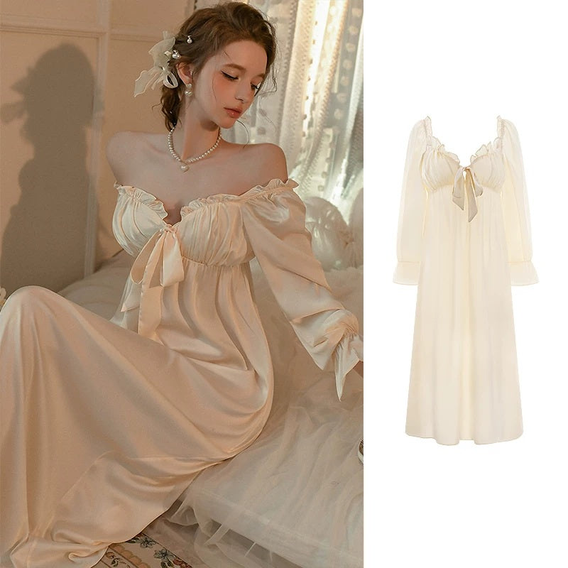 A woman wearing a satin off-the-shoulder nightgown with a large bow at the neckline, shown in a warm indoor setting. A smaller inset on the right shows the same nightgown on a plain white background.