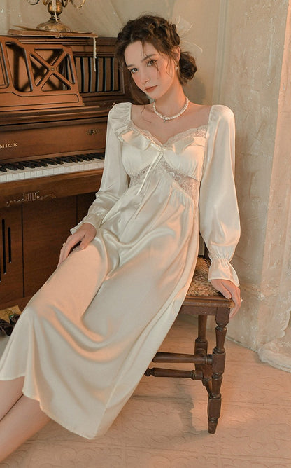 A woman wearing a long-sleeved satin slip dress sits on a wooden chair in a vintage room with a piano in the background.