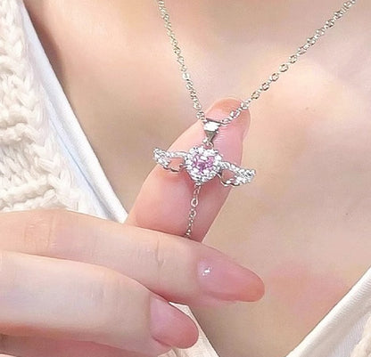 Close-up of a hand holding a silver necklace with a pink gemstone pendant.