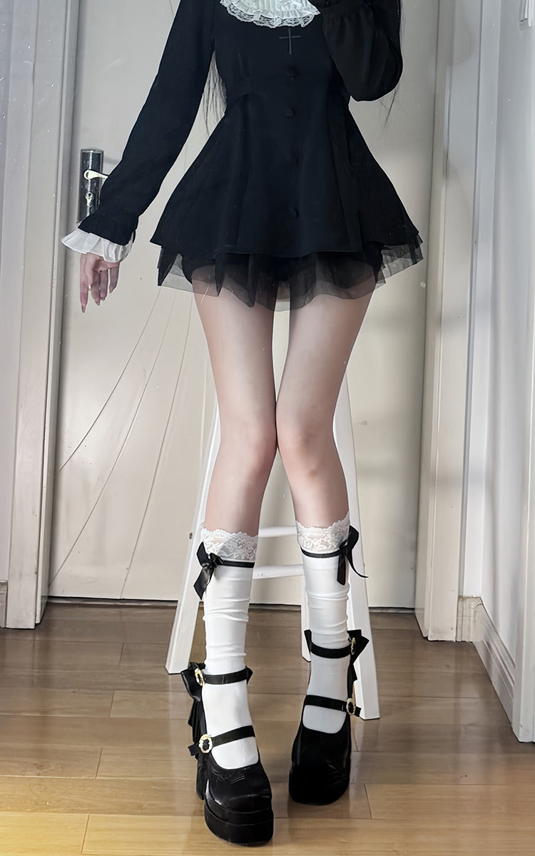 Person wearing a black outfit with white lace details in a room.