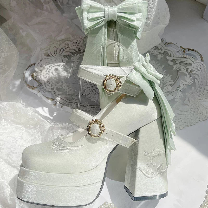 Light green high-heeled shoes with decorative bows and ribbons on a white lace background