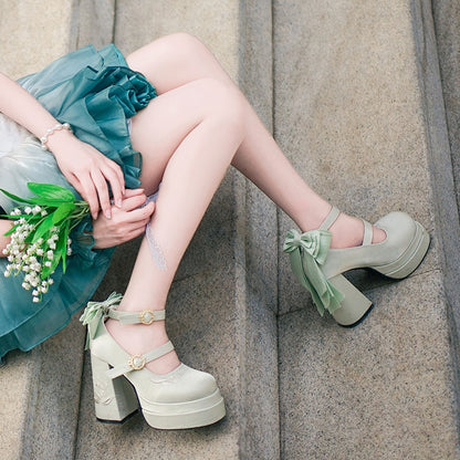 Person wearing light green platform shoes with floral details, sitting on a stone surface.
