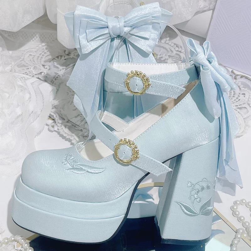 Light blue platform shoes with decorative bows and gold accents on a white lace background