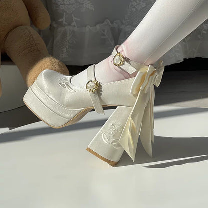 White platform shoes with decorative ribbons worn by a person sitting on a white surface.