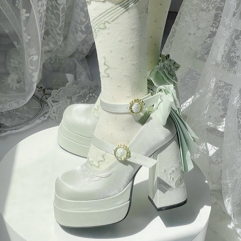 White platform shoes with decorative straps and ribbons on a white background