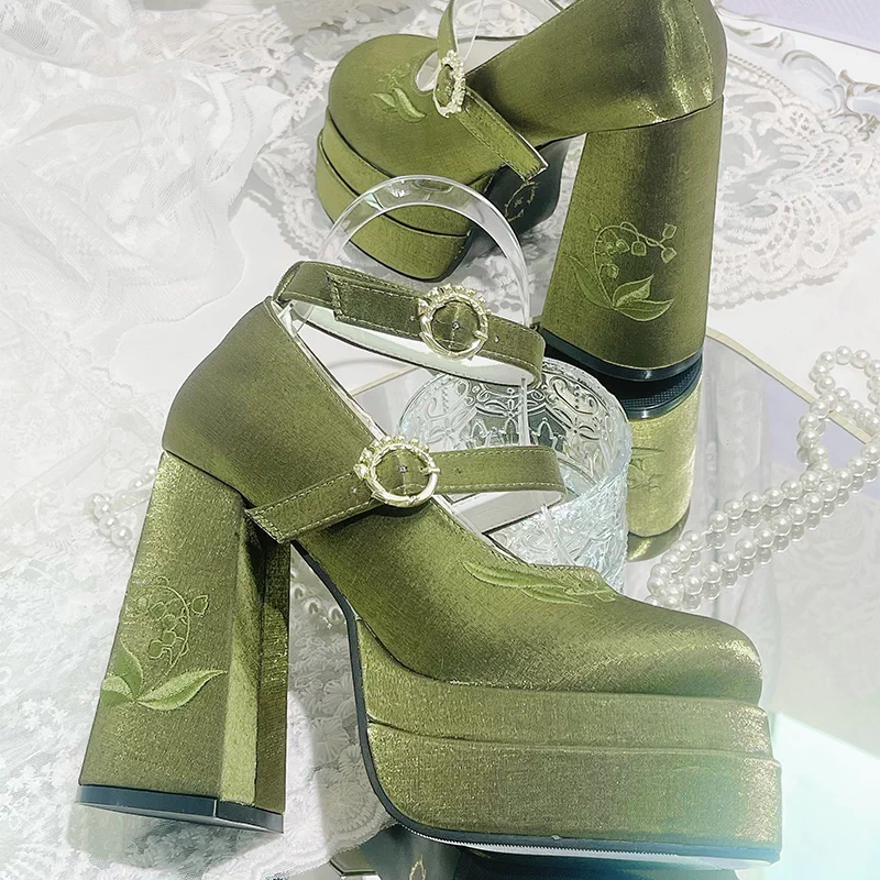 Green platform shoes with floral designs on a white lace background