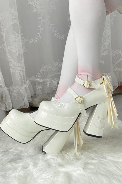 White platform shoes with ribbons worn by a person in a white outfit.