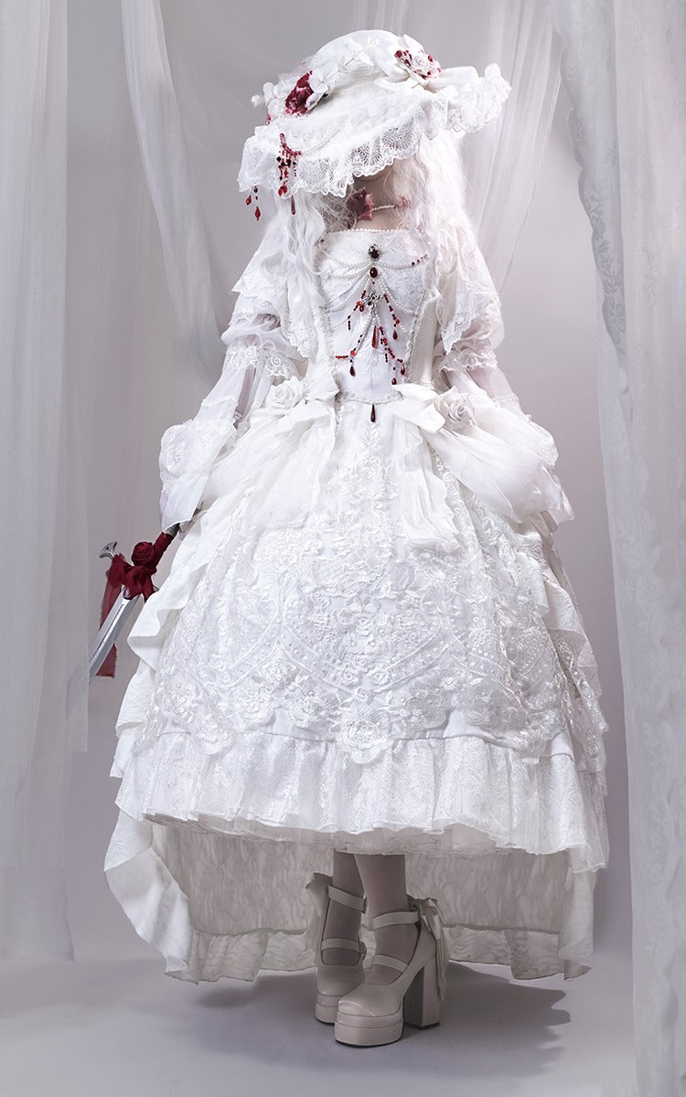 Person wearing a white lace dress with a hood against a plain background