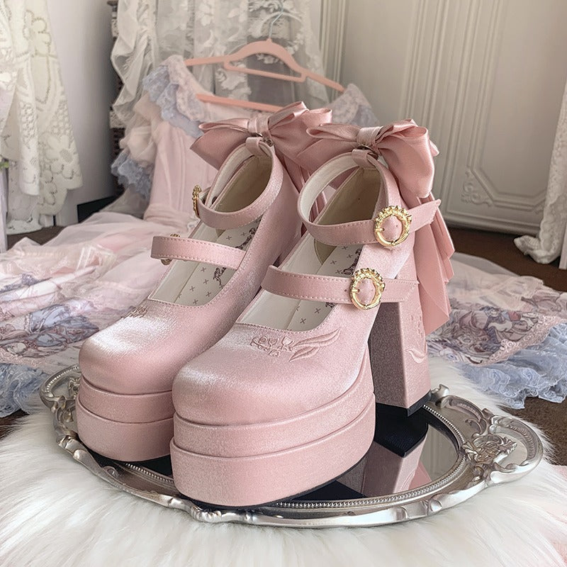 Pink platform shoes with bows on a silver tray in a decorative setting