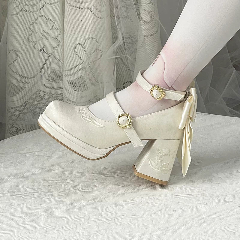 White platform shoes with decorative bow and strap on a white background