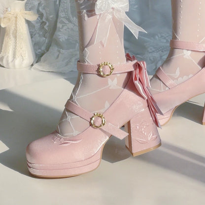 Pink platform boots with gold buckles and sheer fabric on a light background
