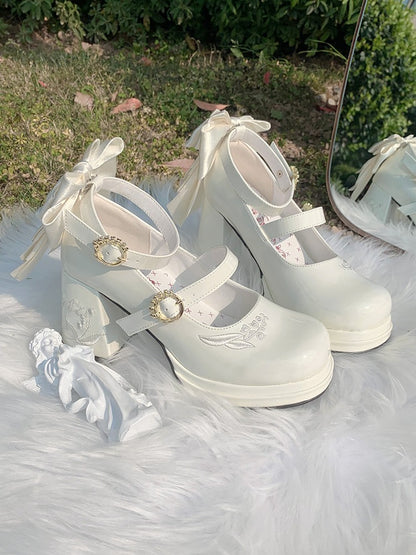 White platform shoes with decorative bows and embellishments on a fluffy white surface.