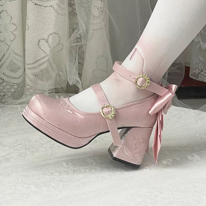 Pink platform shoes with decorative straps and a bow on a white lace background