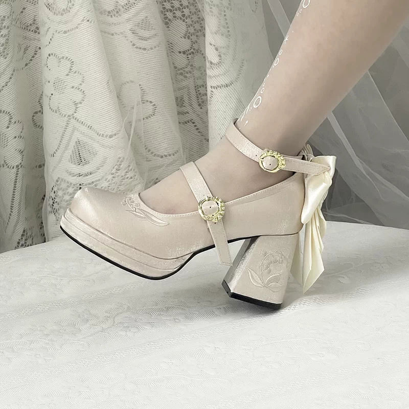Beige high-heeled shoes with decorative bow and straps on a light background