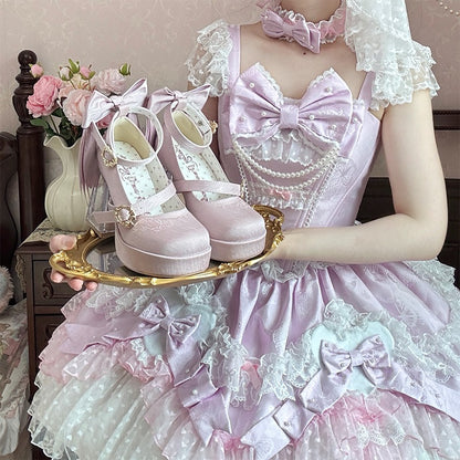 Person in a pink and white dress holding a tray with pink shoes