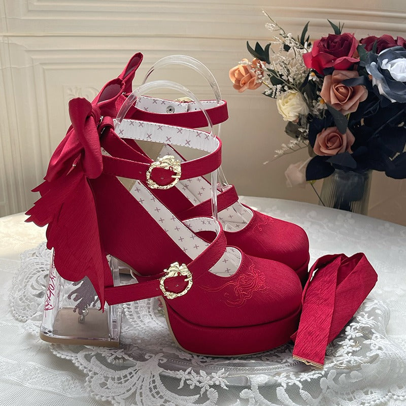 Red high-heeled shoes with floral decorations on a lace tablecloth.