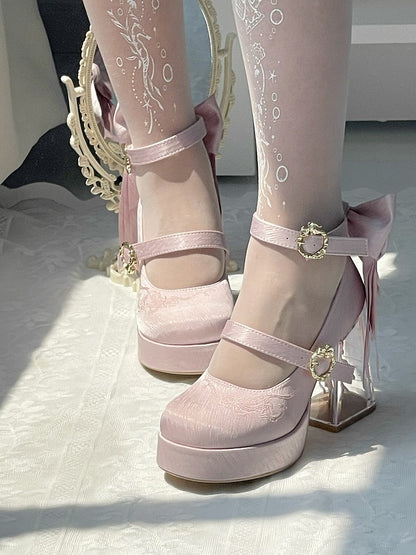 Pink platform shoes with decorative straps on a light background