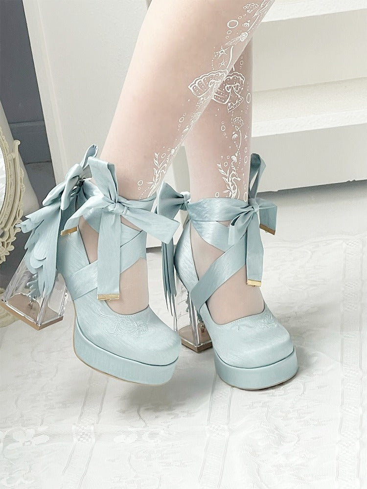 Light blue platform shoes with bows worn with sheer white stockings on a light background