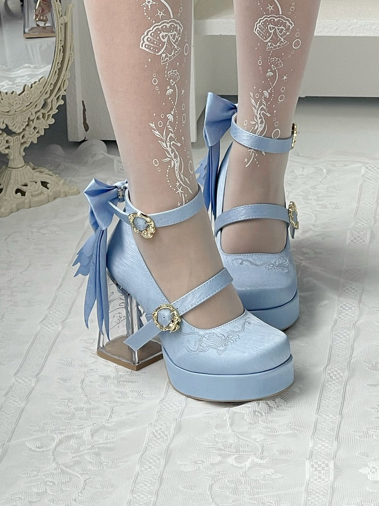 Light blue high-heeled shoes with decorative ribbons on a white floor.
