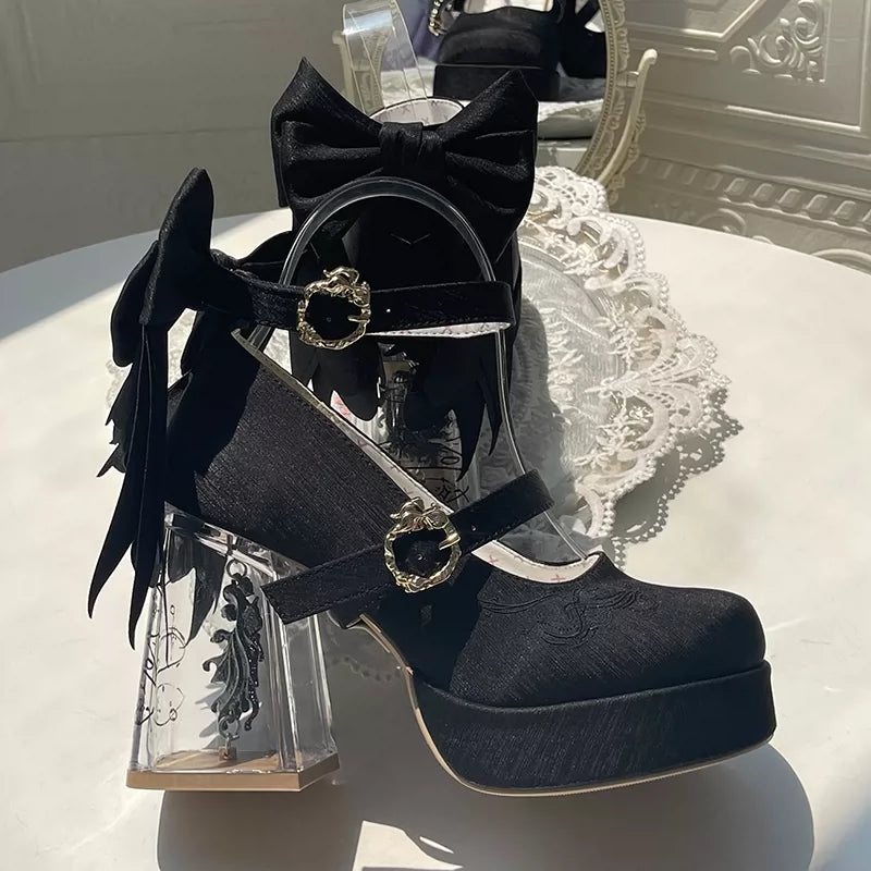 Black high-heeled shoes with bows on a decorative table
