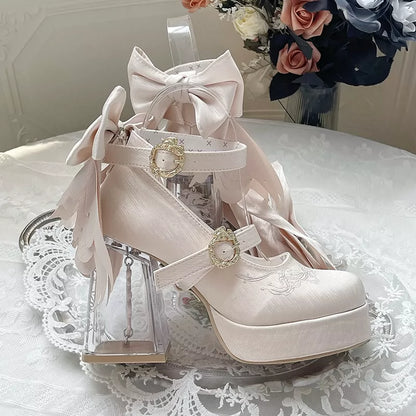 White high-heeled shoes with decorative bows and pearls on a lace tablecloth.