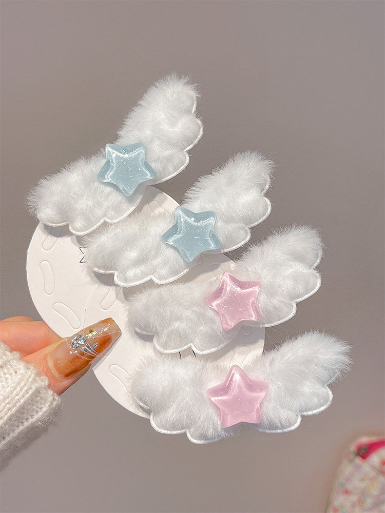 Four white fluffy cloud-shaped hair clips with star accents in light blue and pink, held on a white display card by a hand with glittery nail polish.