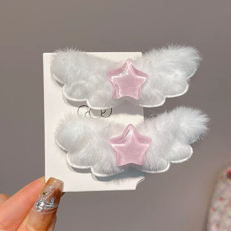 Two fluffy white cloud-shaped hair clips with pink star accents, displayed on a white card held by a hand.