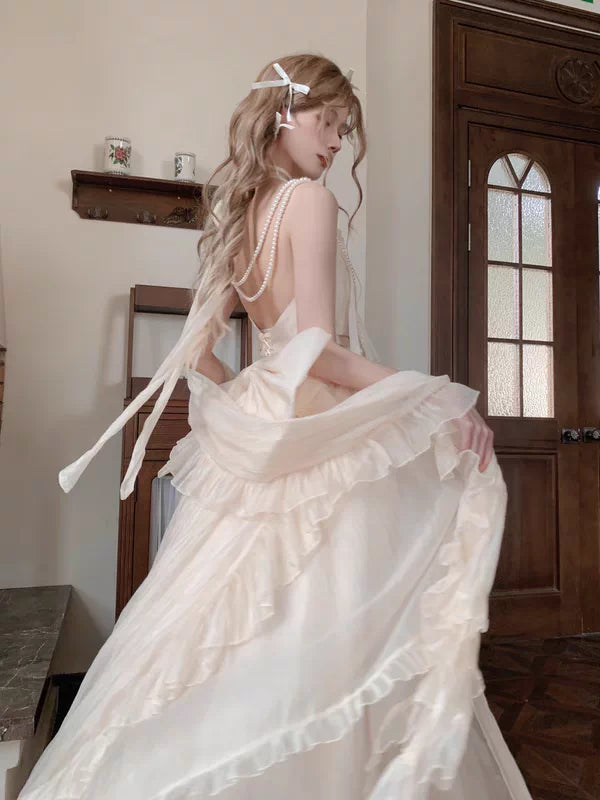 Woman in a white wedding dress with long train sitting in a room with wooden door and window.