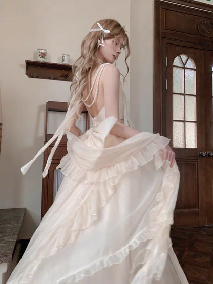 Woman in a white wedding dress with long train sitting in a room with wooden door and window.