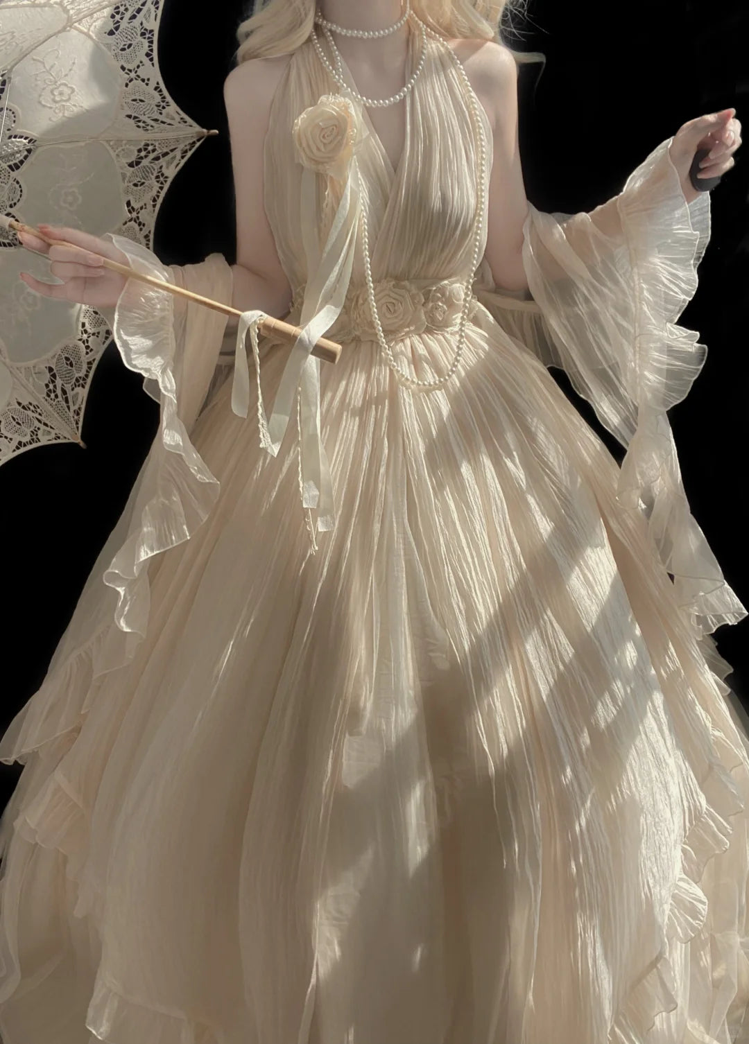 Woman in a white dress holding a lace parasol against a black background