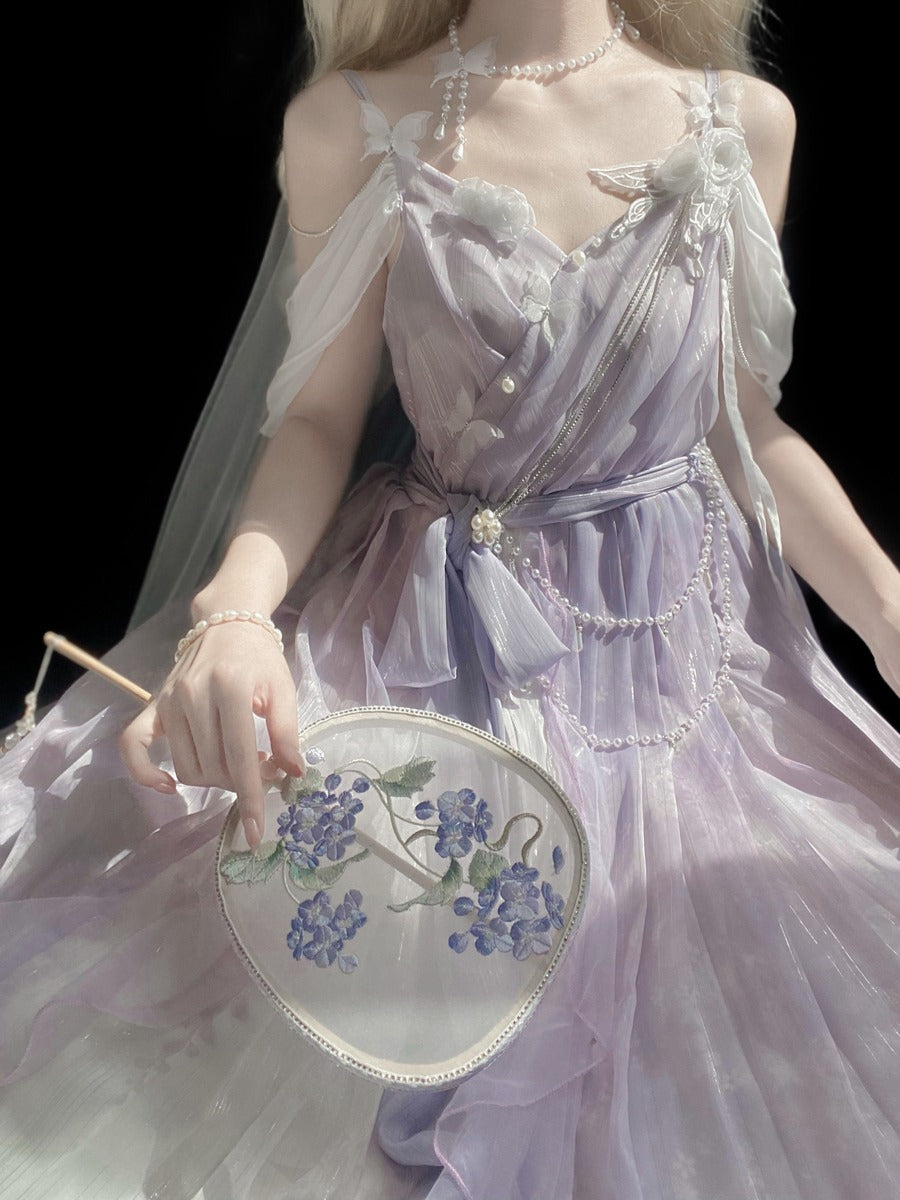 A model wearing a lavender and white sheer Lolita-style dress with pearl embellishments, holding a white embroidered fan with blue flowers against a solid black background.
