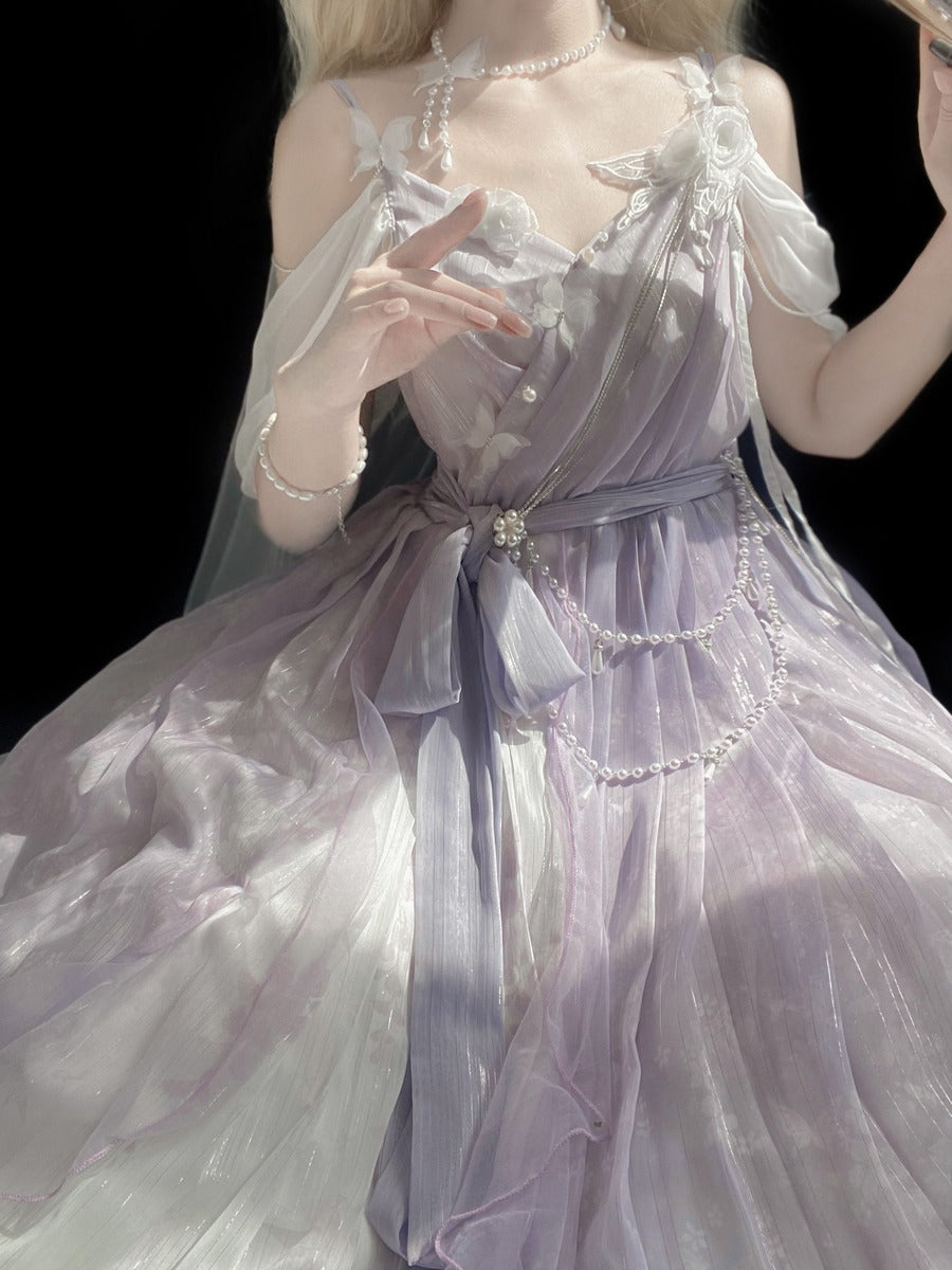 A model wearing a lavender and white sheer tulle dress with pearl-like bead details, photographed against a solid black background.