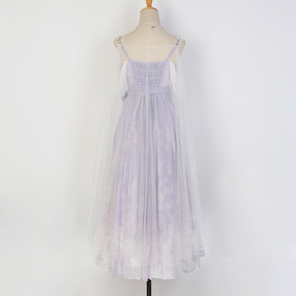 A sleeveless, floor-length tulle dress in a very pale lavender or lilac tone, displayed on a mannequin against a plain white background. The dress has thin straps, a gathered bodice, and a sheer overlay.