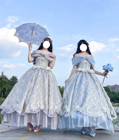 Two women wearing matching off-the-shoulder light blue and white lace ballgowns stand outdoors under a blue sky, one holding a matching parasol and the other holding a bouquet of blue flowers.