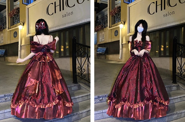 A woman modeling a voluminous off-the-shoulder ball gown in an outdoor nighttime setting. The dress is a rich metallic burgundy with coppery-gold sheen and ruffled trim.