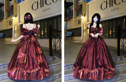 A woman modeling a voluminous off-the-shoulder ball gown in an outdoor nighttime setting. The dress is a rich metallic burgundy with coppery-gold sheen and ruffled trim.