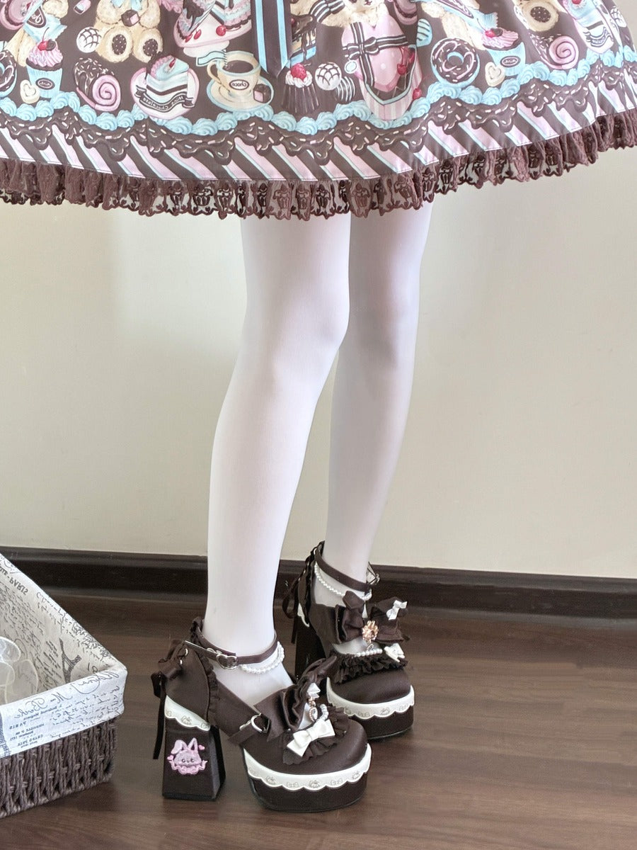 A person wearing a brown and white patterned Lolita skirt, white tights, and brown platform Mary Jane shoes with white lace details, standing on a wooden floor.