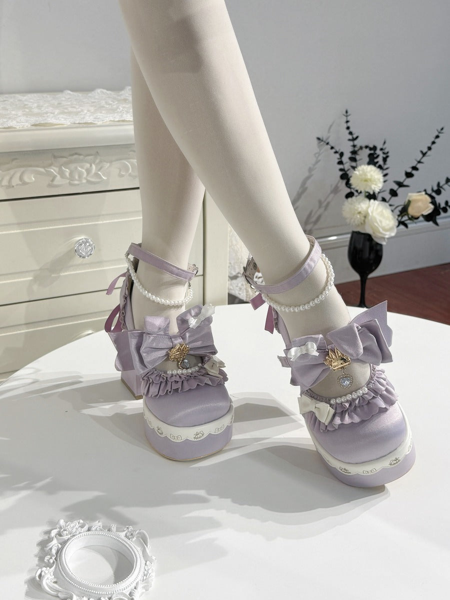 A pair of lavender platform Lolita-style shoes with bows, lace trim, and pearl details, shown on a mannequin leg in an indoor room setting.