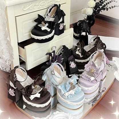 A collection of pastel Lolita-style platform shoes displayed on a mirrored tray and a small cream cabinet, featuring black, lavender, light blue, and pink designs with lace, bows, and decorative accents.