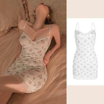 A woman reclines on a bed wearing a fitted floral lingerie dress in a warm beige tone, with a smaller inset on the right showing the same dress on a plain white background. The dress has thin straps, a sweetheart neckline, ruched detailing, and a lace hem.