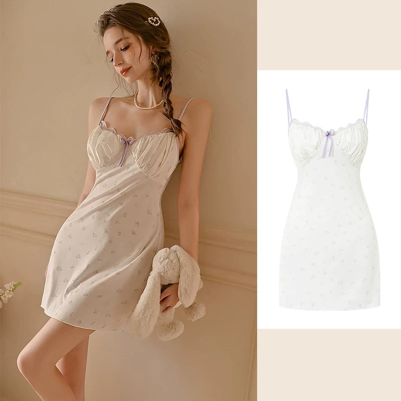 A woman models a short white slip dress with a subtle floral print and lace cups, holding a plush bunny accessory. The image is split, with the model on the left and a clean product-only view of the dress on the right.