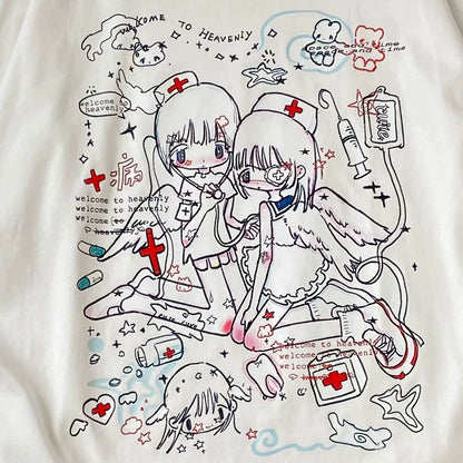 A close-up of a white graphic t-shirt featuring a detailed anime-style illustration of two angelic female characters dressed as nurses, surrounded by medical doodles, crosses, and text reading 'Welcome to Heaven'.