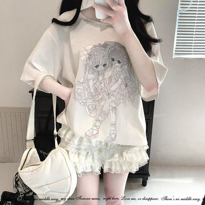 A person wearing a cream-colored oversized t-shirt with a detailed anime girl graphic on the front, paired with matching cream lace-up shorts and carrying a cream shoulder bag.
