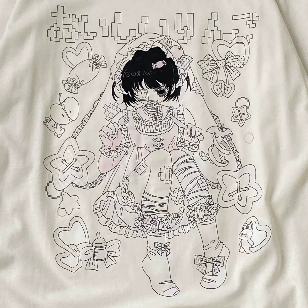 A close-up of a cream-colored fabric garment featuring a detailed black line art graphic of a cute anime-style girl in a frilly dress, surrounded by decorative motifs like bows, stars, and hearts.