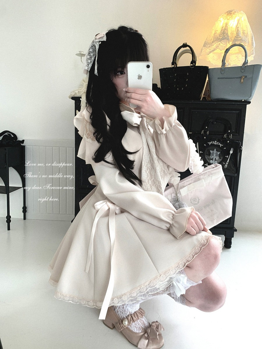 A person takes a mirror selfie wearing a cream-colored Lolita-style dress with lace details, ruffled sleeves, and a bow headband, holding a light pink clutch bag in a room with handbags on a black cabinet.