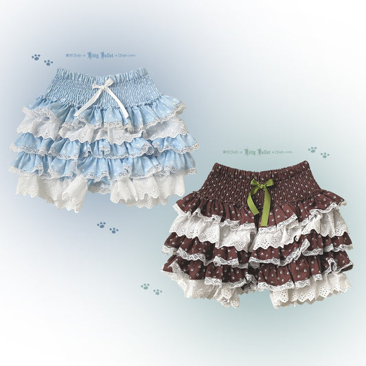 Two pairs of ruffled bloomers, one blue and white, one brown with a green bow, on a light blue background.