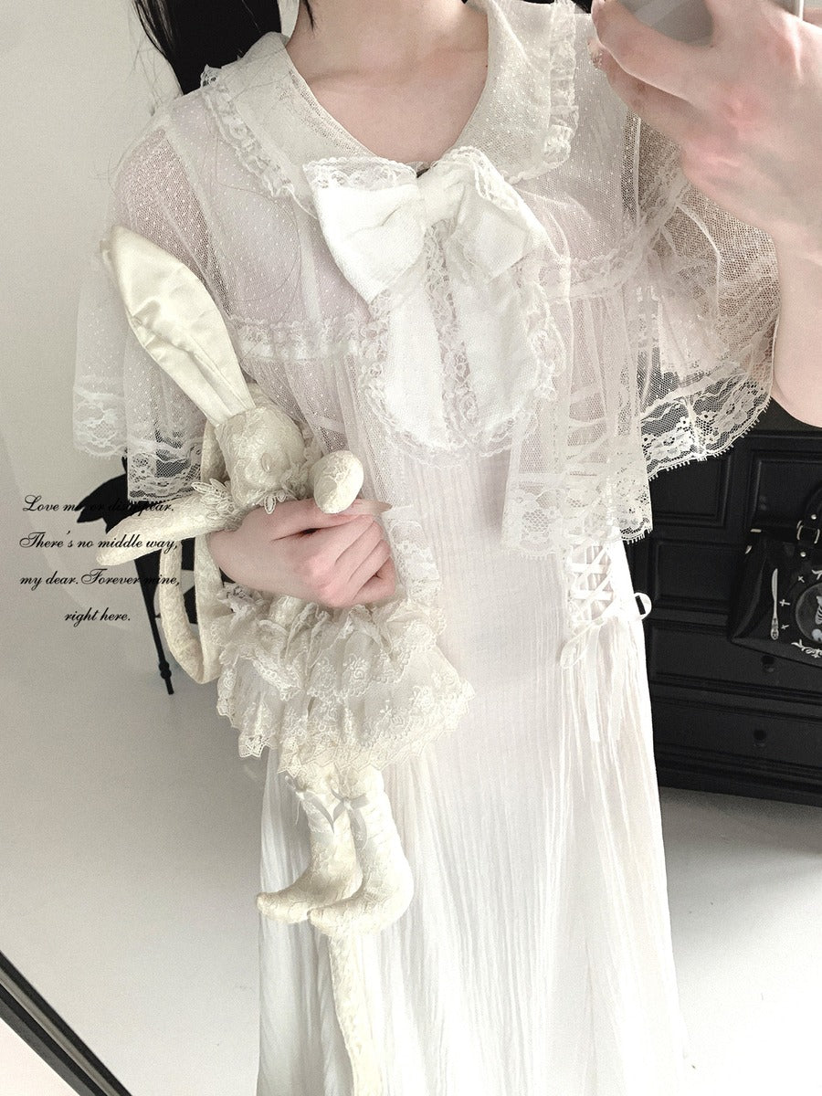Person wearing a white lace dress holding a white rabbit figure.