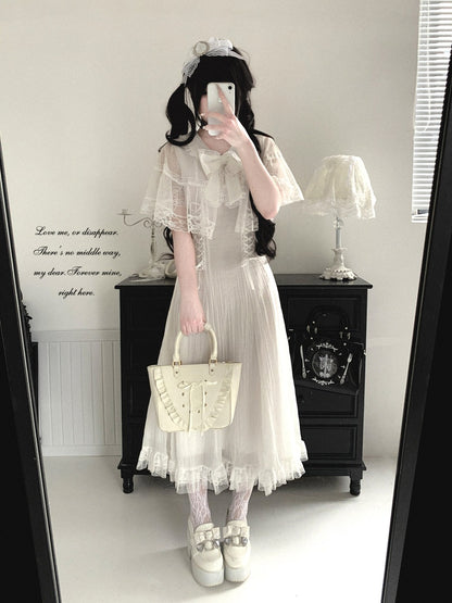 Person wearing a white lace dress holding a beige handbag in a room with a black cabinet and white walls.